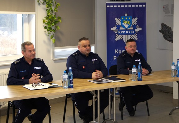 Zdjęcia z odprawy słuzbowej w sali odpraw komendy policji w rukach na których widać uczestników spotkania