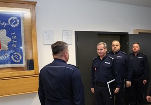 Zdjęcia z odprawy słuzbowej w sali odpraw komendy policji w rukach na których widać uczestników spotkania