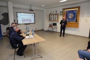 Zdjęcia z odprawy słuzbowej w sali odpraw komendy policji w rukach na których widać uczestników spotkania