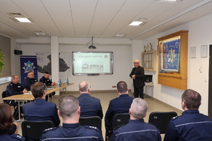 Zdjęcia z odprawy słuzbowej w sali odpraw komendy policji w rukach na których widać uczestników spotkania