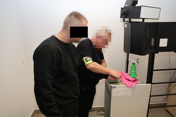 Technik kryminalistyki pobiera odbitki palców od mężczyzny zatrzymanego