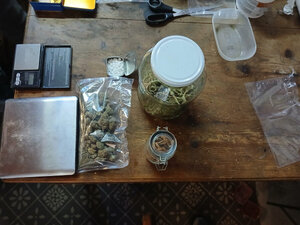 Zabezpieczone środki odurzające zapakowane w woreczki foliowe, wagi i pudełka ustawione na drewnianym stole