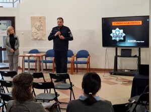 Policjant podczas prelekcji w szkole trzyma w ręku mikrofon.