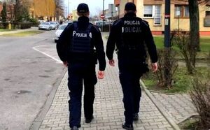 Dwóch policjantów idzie chodnikiem przez miasto