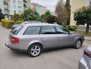 samochód marki audi typu kombi zaparkowany na parkingu w tle inne pojazdy i bloki mieszkalne.