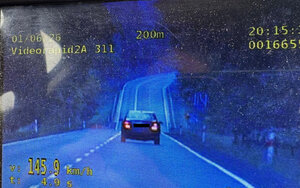 Zdjęcie ekranu videorejestratora na którym jest pojazd z zmierzona prędkością oraz droga dodatkowo widoczne sa parametry pracy urządzenia wyświetlone cyframi koloru żółtego w tym prędkość
