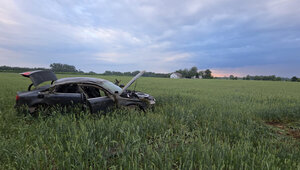 samochód marki audi uszkodzony w wyniku dachowania stoi w polu porośniętym zbożem w tle zbudowania