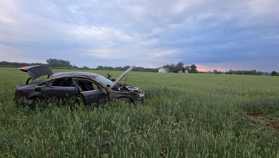 samochód marki audi uszkodzony w wyniku dachowania stoi w polu porośniętym zbożem w tle zbudowania