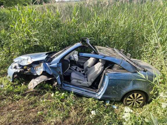 samochód osobowy volkswagen koloru niebieskiego uszkodzony w wyniku zdarzenia drogowego stojący w zaroślach stawu