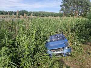 samochód osobowy volkswagen koloru niebieskiego uszkodzony w wyniku zdarzenia drogowego stojący w zaroślach stawu