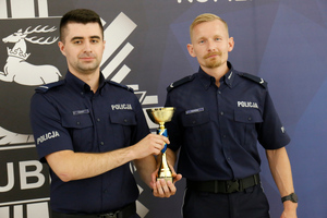 Dwóch policjantów umundurowanych trzyma puchar