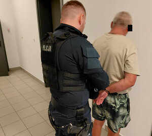 Policjant zakłada kajdanki zatrzymanemu mężczyźnie