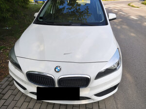 Pojazd marki BMW koloru białego z uszkodzona pokrywa silnika