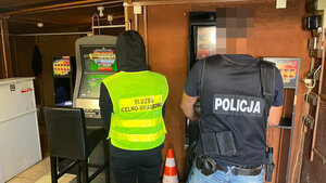 Policjant i funkcjonariusza służby celno-skarbowej stoją przy automatach do gier