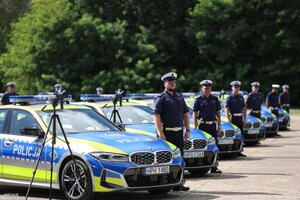 5 Radiowozów policyjny oznakowane marki BMW  ustawione w rzędzie obok których stoją policjanci oraz mierniki prędkości na statywie