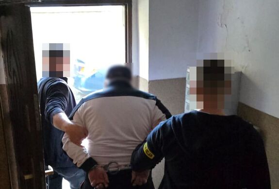 Policjanci prowadzą zatrzymanego mężczyznę.