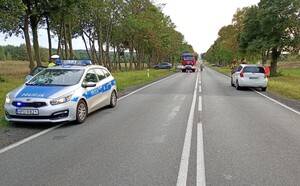 Miejsce zdarzenia drogowego. Pojazdy służb policji i służby drogowej na  jezdni oraz samochody osobowe uszkodzone w zdarzeniu drogowym.