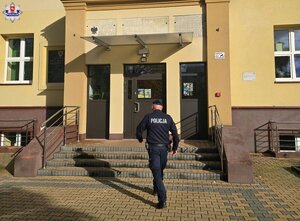 Policjant idzie w stronę budynku szkoły